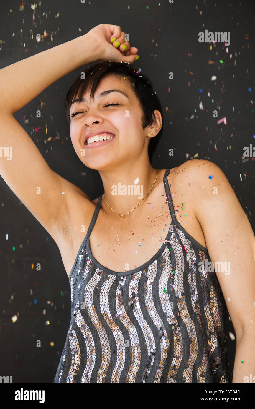 Smiling mixed race woman dancing in confetti Stock Photo