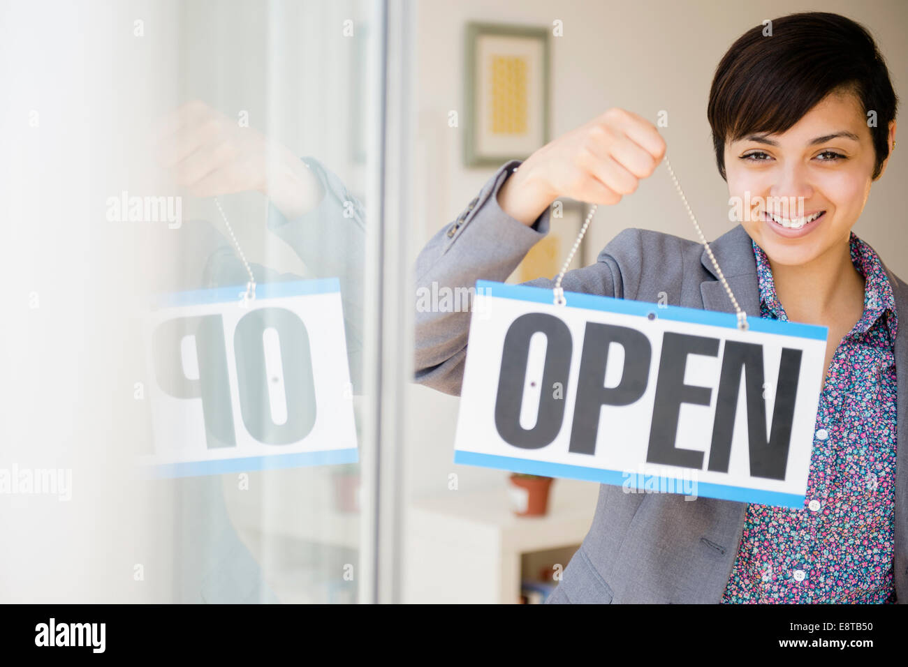 Mixed race businesswoman holding open sign Stock Photo