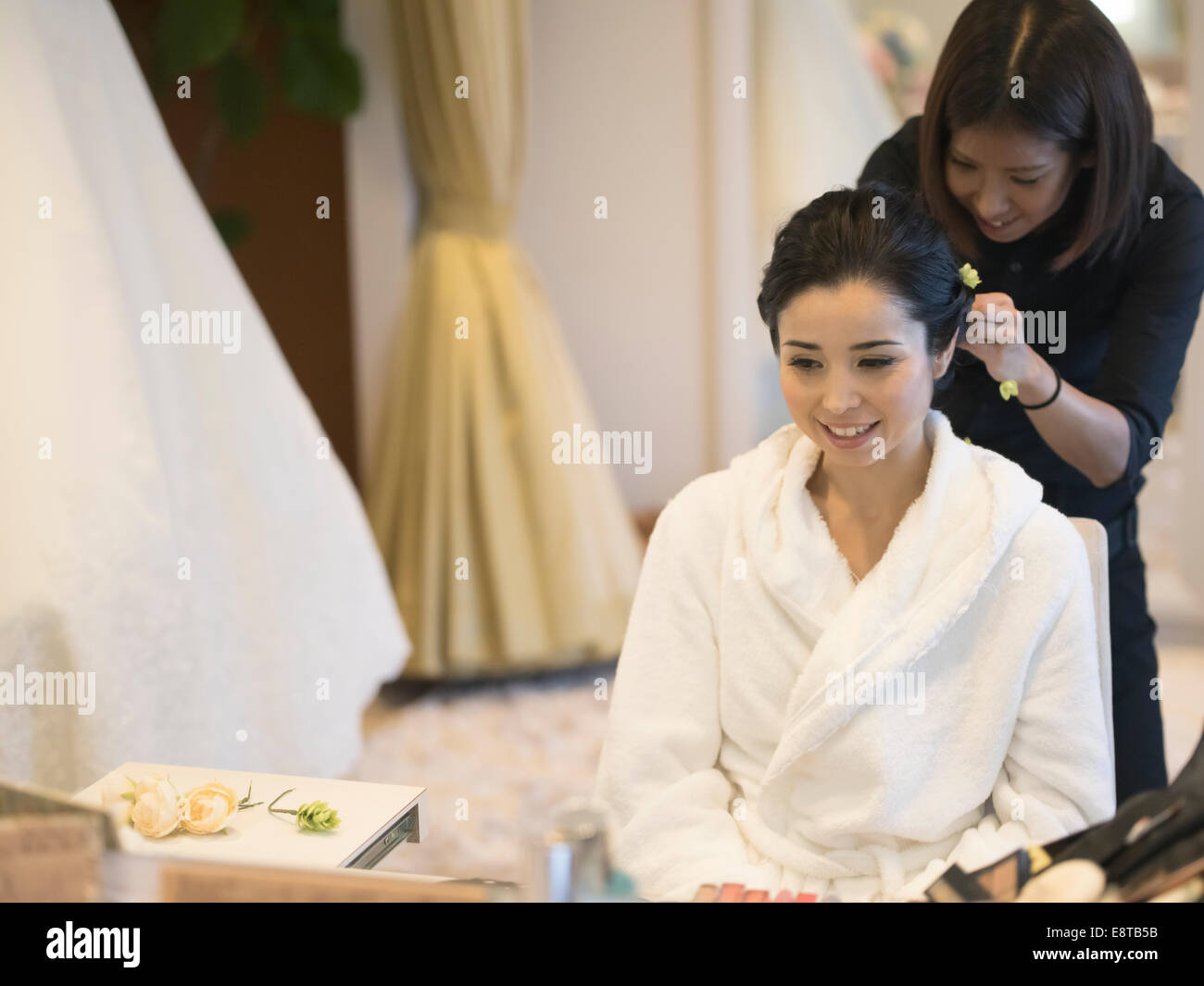 Mixed race, Asian / American bride has makeup and hair styled by stylist before wedding Stock Photo