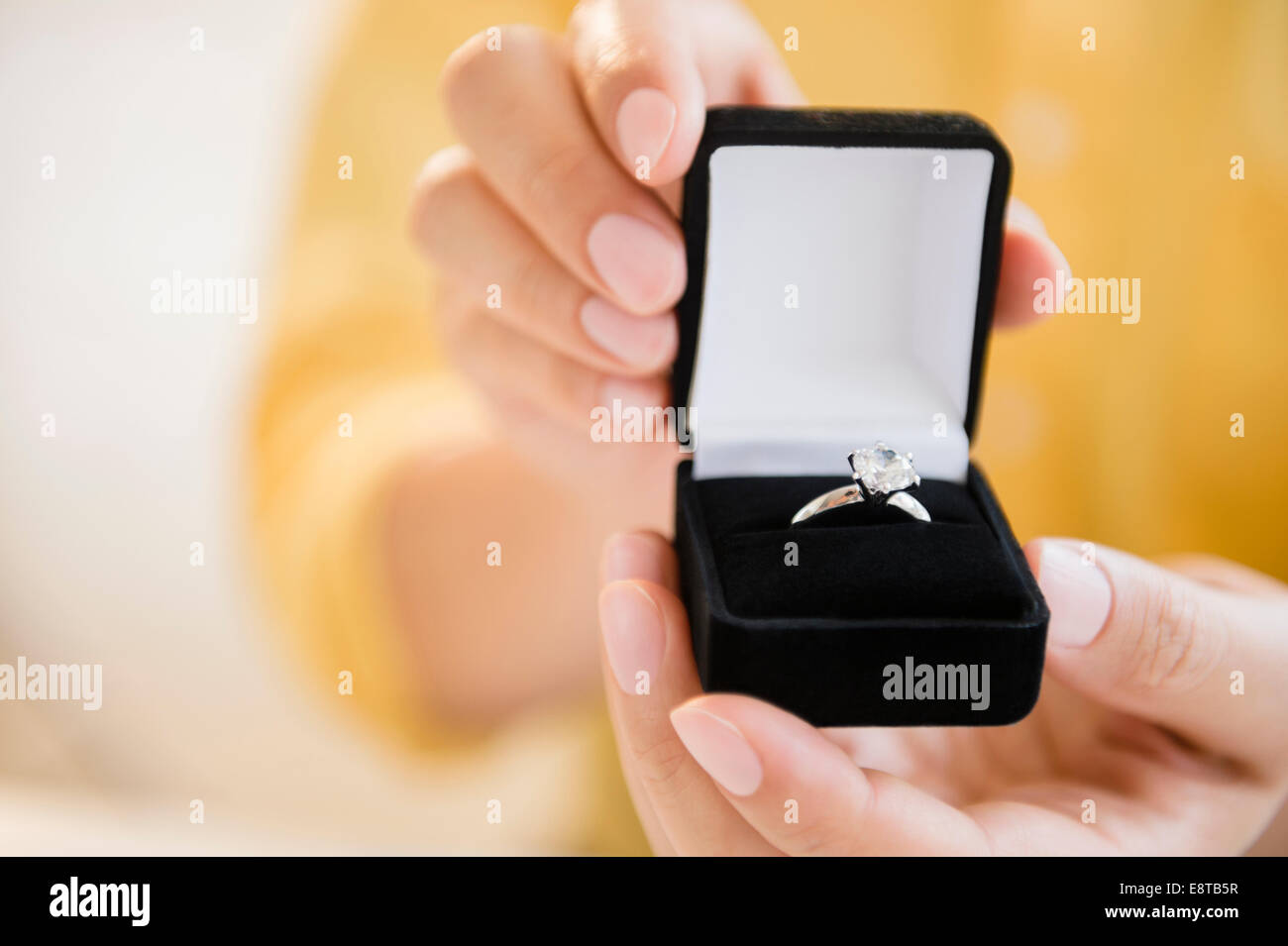 Mixed race man holding engagement ring in box Stock Photo