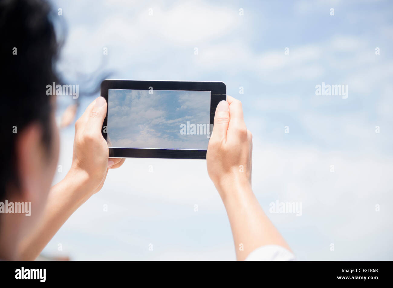 Close up of mixed race man photographing clouds with digital tablet Stock Photo