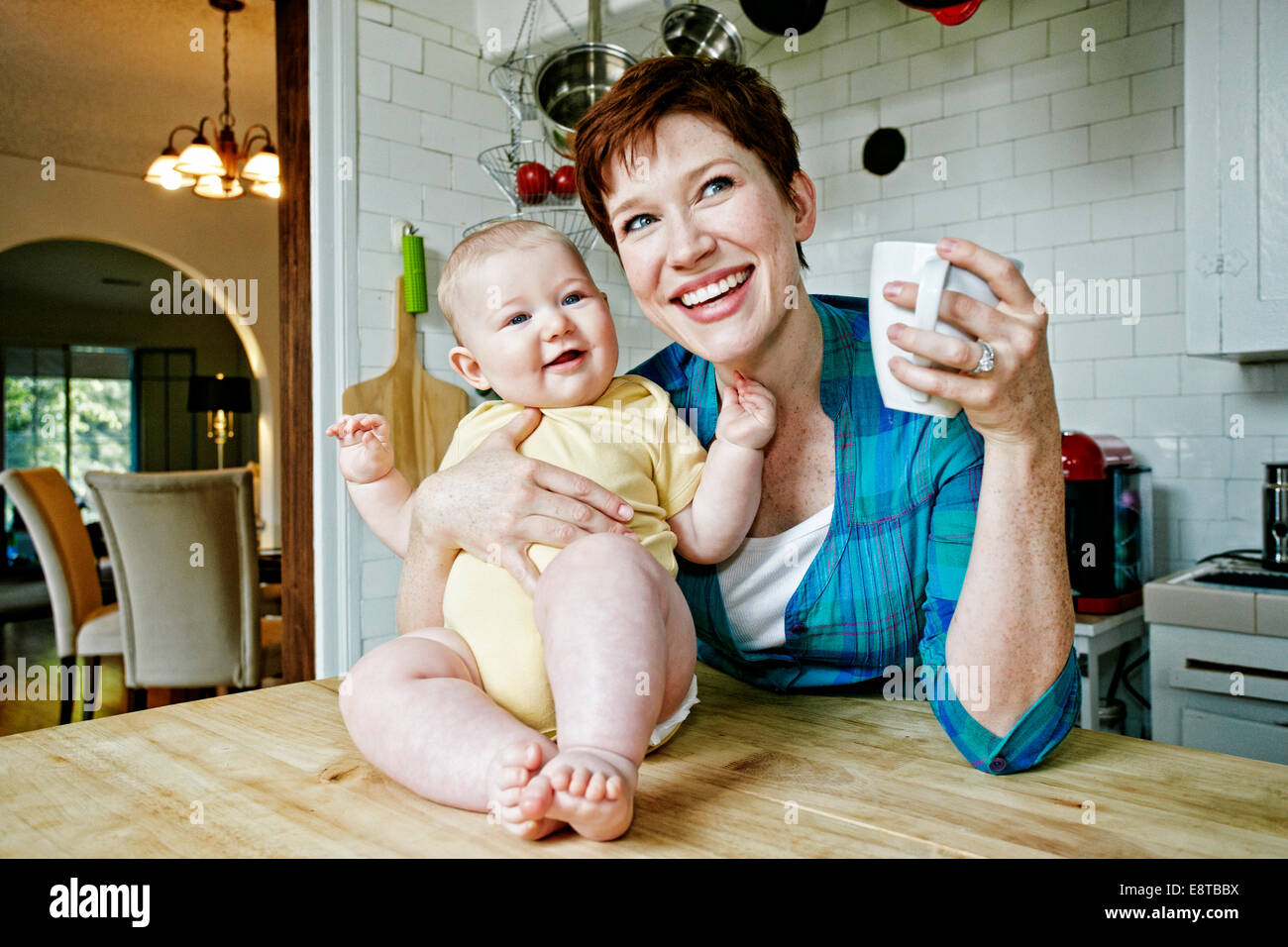 Caucasian mother and baby relaxing in kitchen Stock Photo