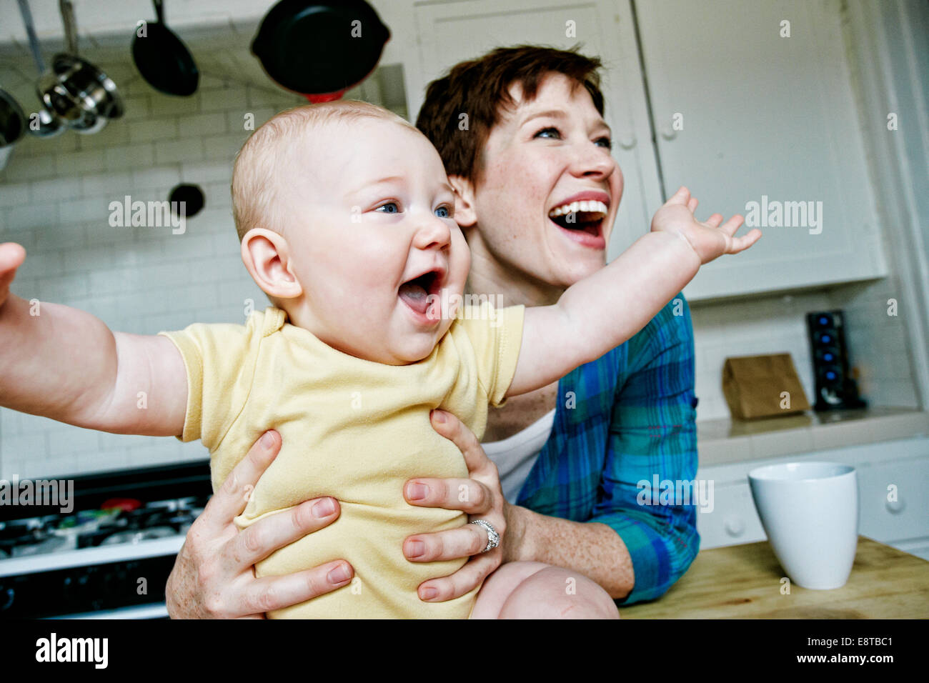 Caucasian mother and baby relaxing in kitchen Stock Photo