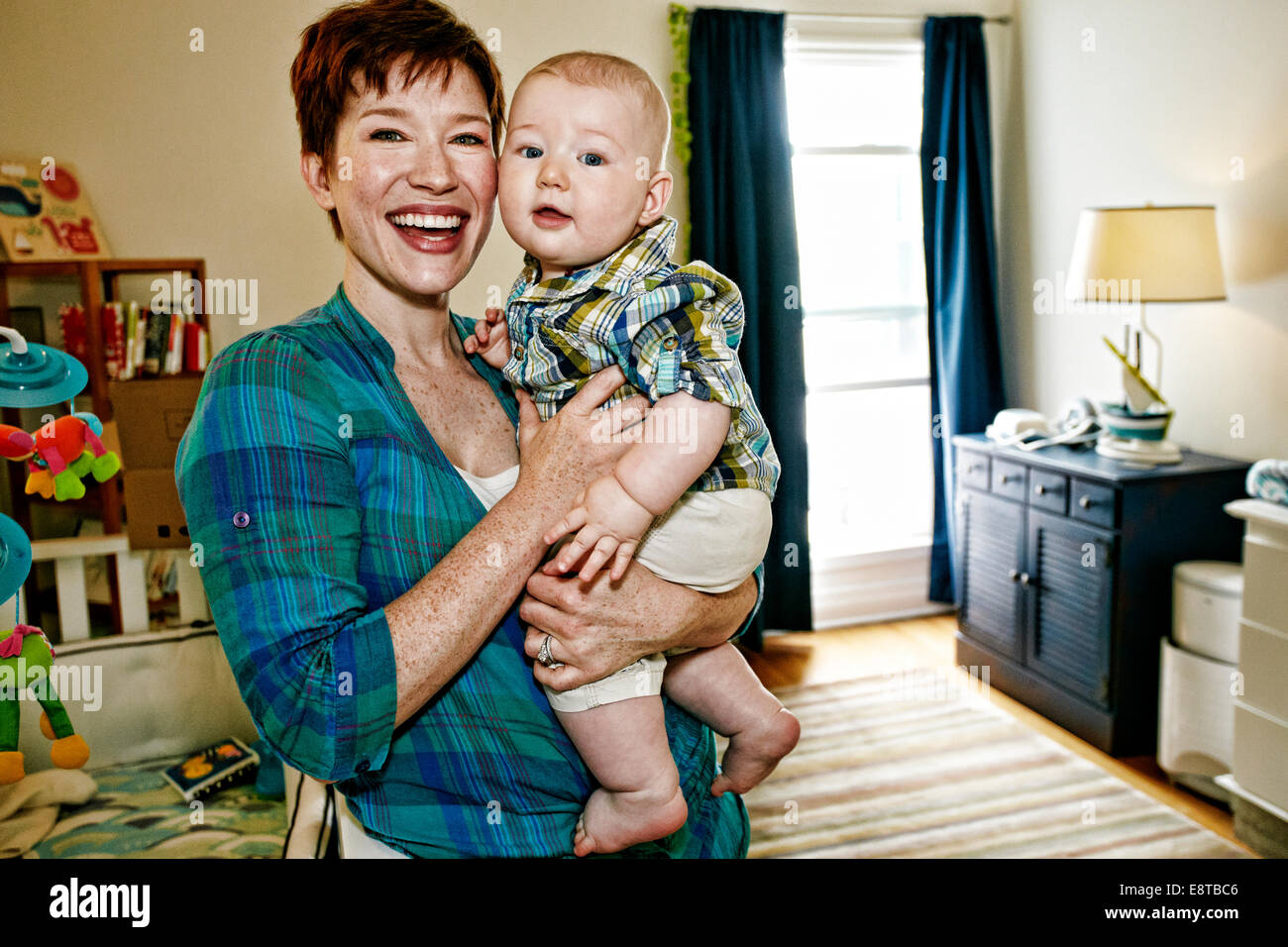 Caucasian mother holding baby in bedroom Stock Photo