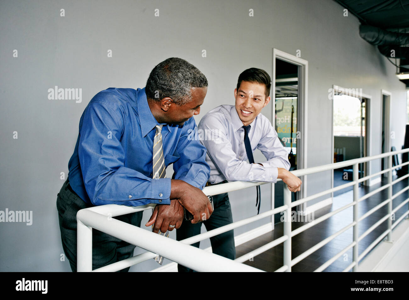 Businessmen talking at railing Stock Photo