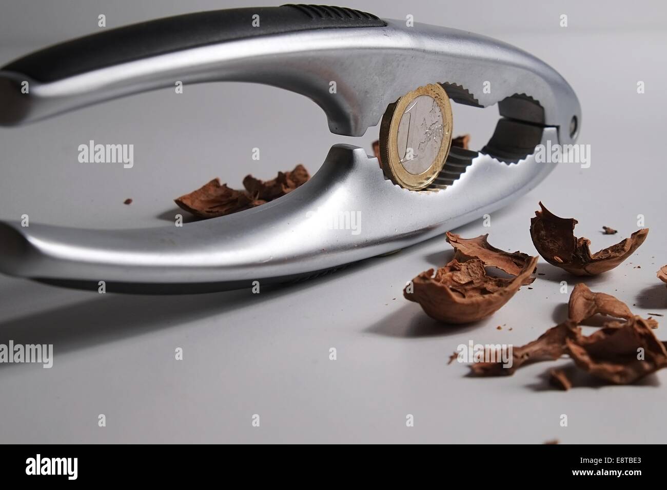 Cracking a nut with a nutcracker to find one Euro inside Stock Photo