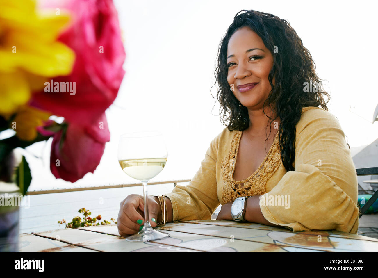 Mixed race woman drinking wine at waterfront Stock Photo
