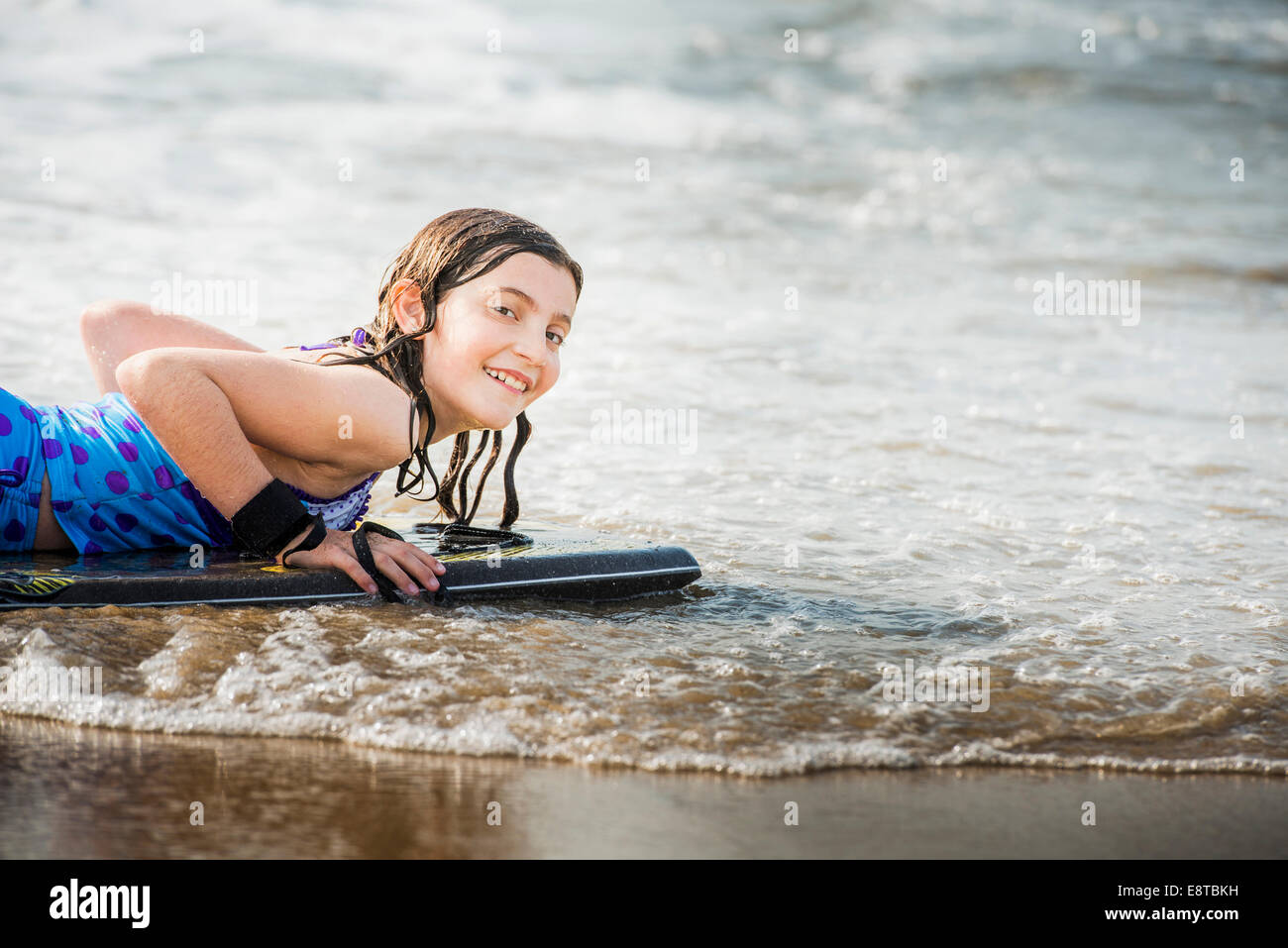 Mixed race girl riding boogie board at beach Stock Photo Alamy