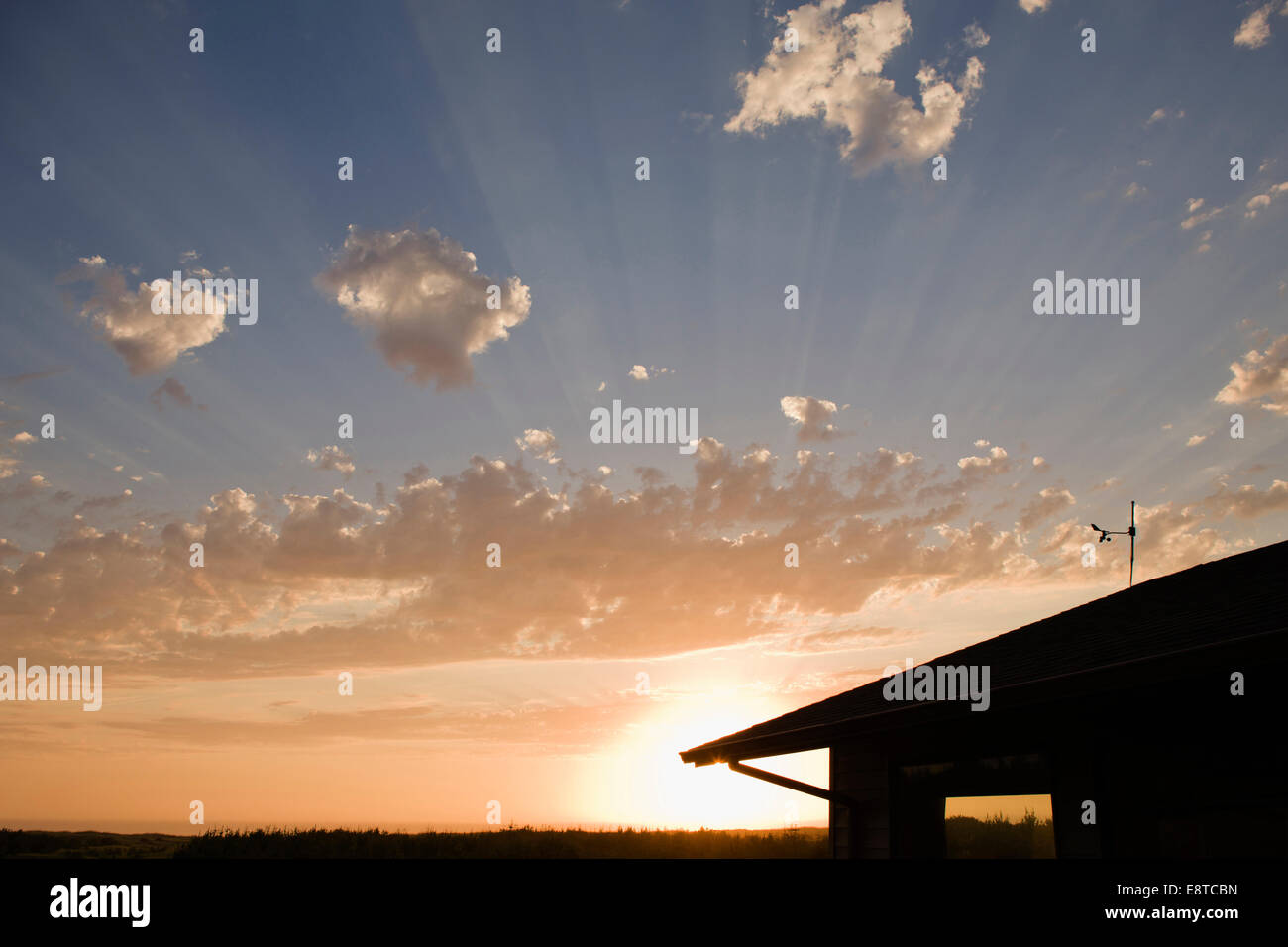 Sunbeams through clouds over house Stock Photo