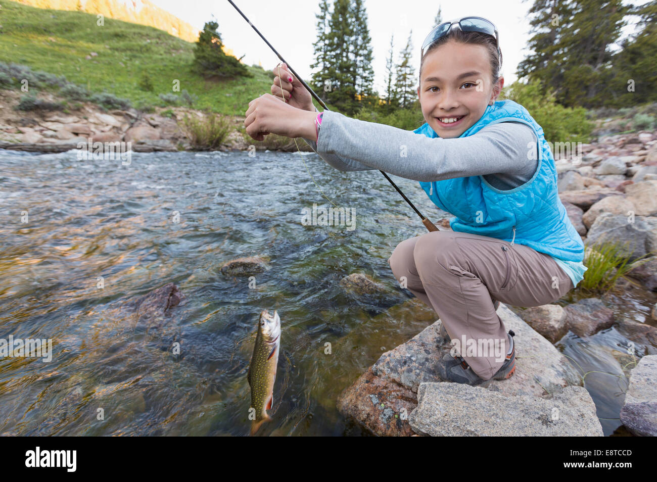 Mixed race girl fishing in river Stock Photo
