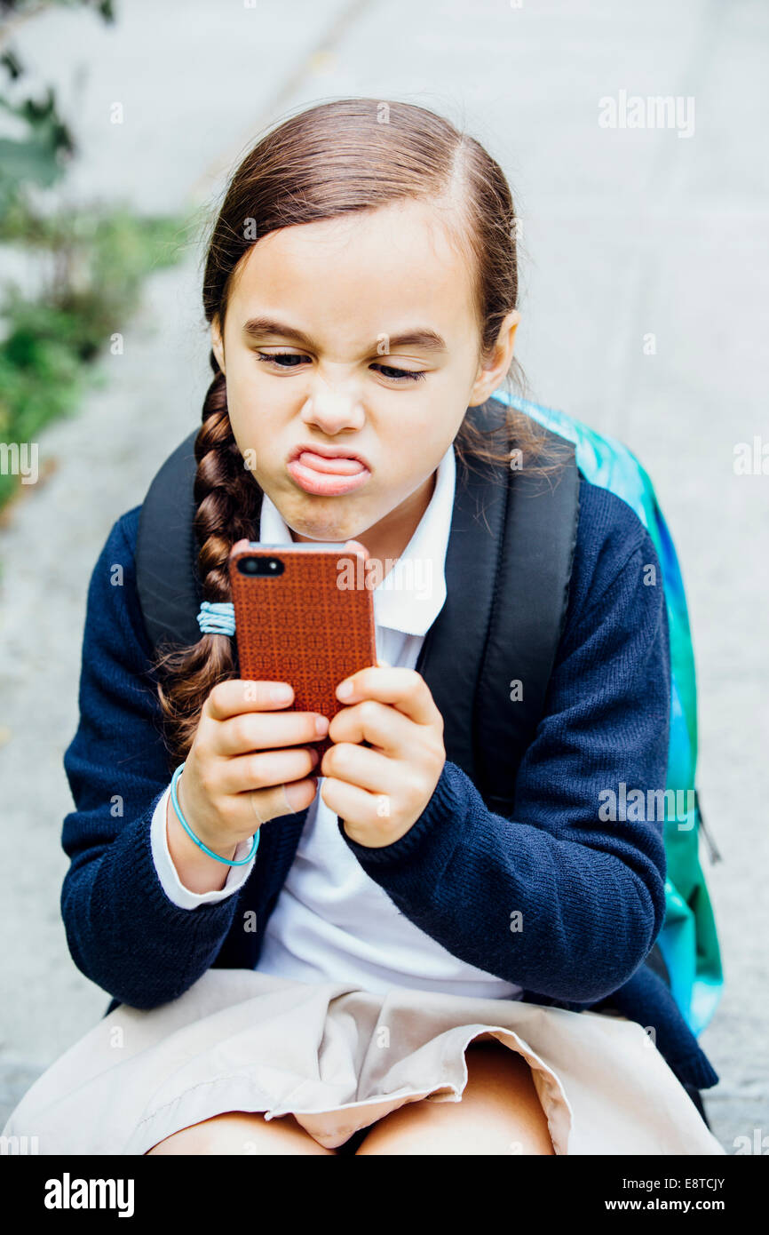 Mixed race girl making a face at cell phone Stock Photo