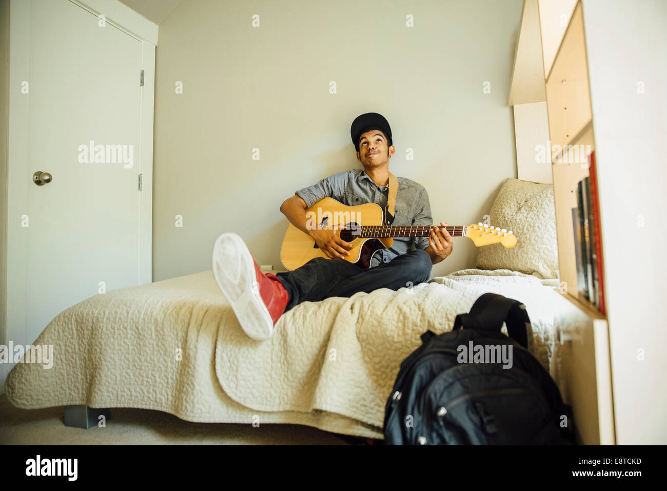Mixed race boy playing guitar in bedroom Stock Photo Alamy