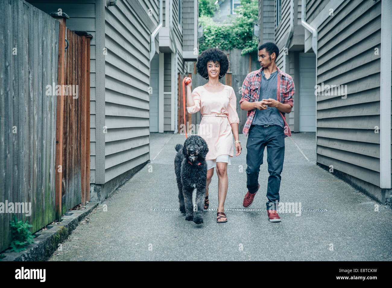 Mixed race mother and son walking dog in suburban apartment complex Stock Photo