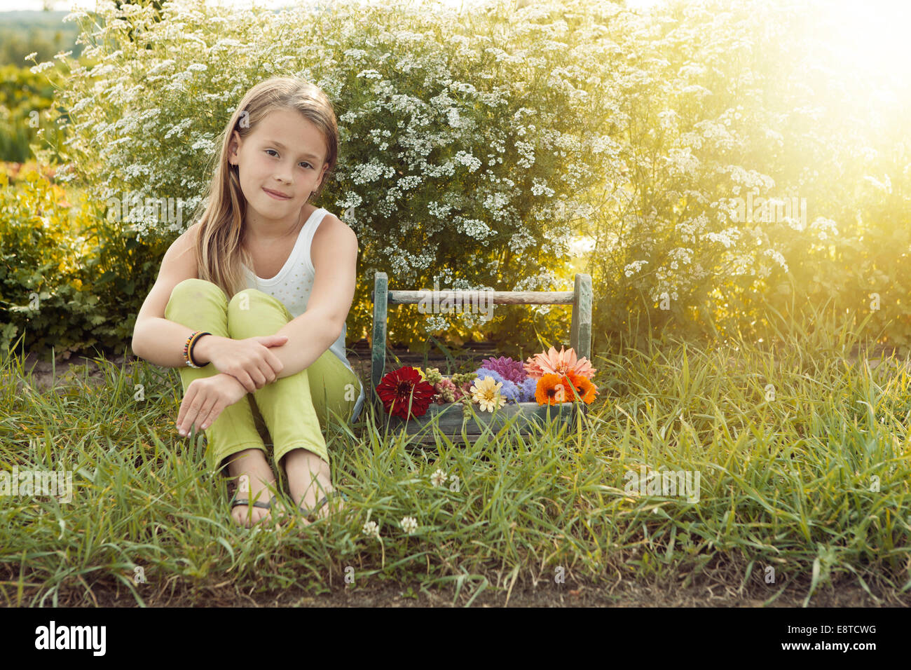 Caucasian girl sitting with basket of flowers Stock Photo
