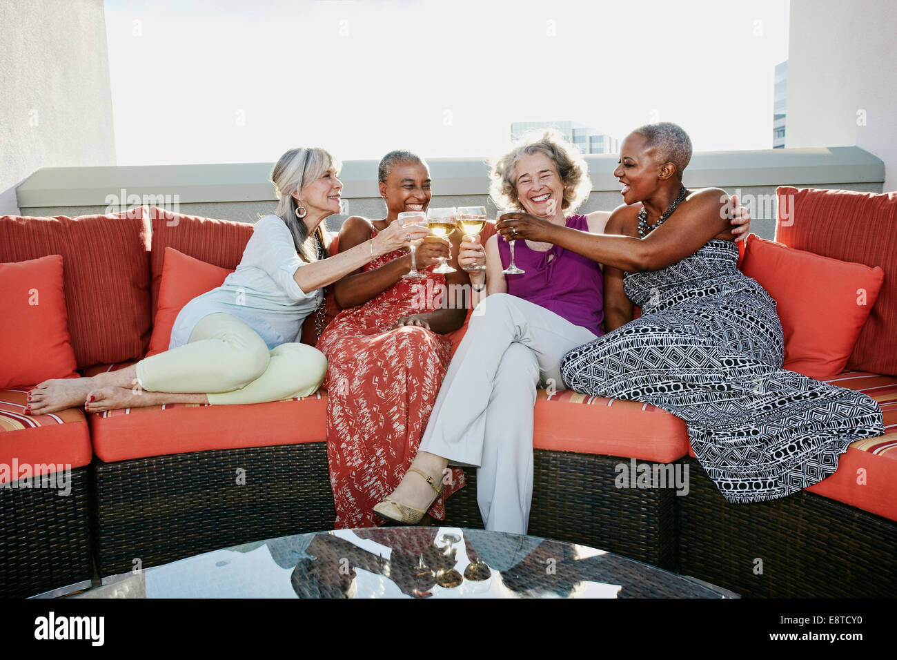 Women toasting each other with wine on urban rooftop Stock Photo