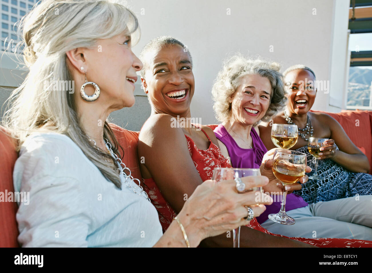 Women drinking wine together on urban rooftop Stock Photo