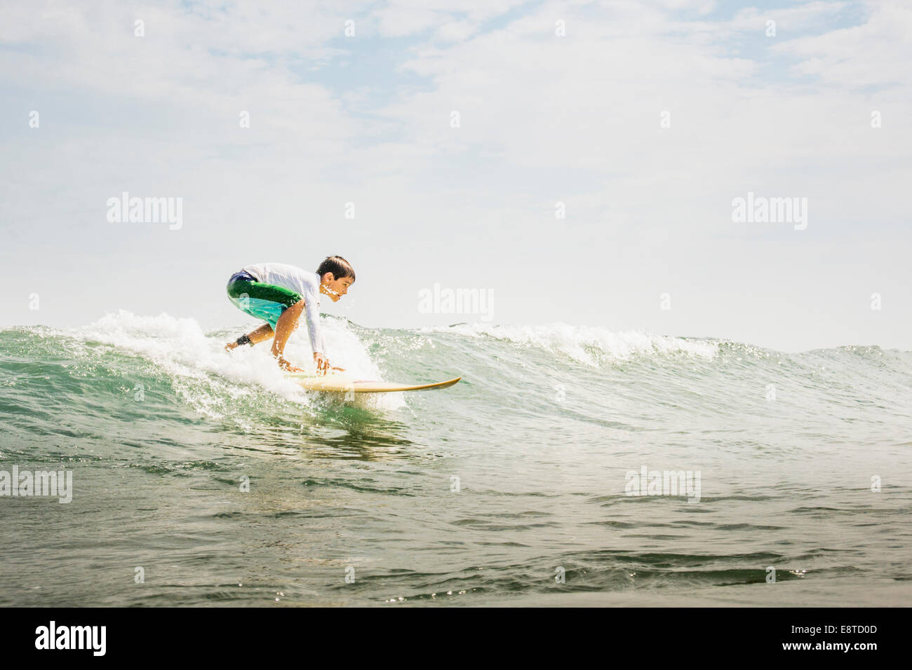 Mixed race boy surfing in waves Stock Photo