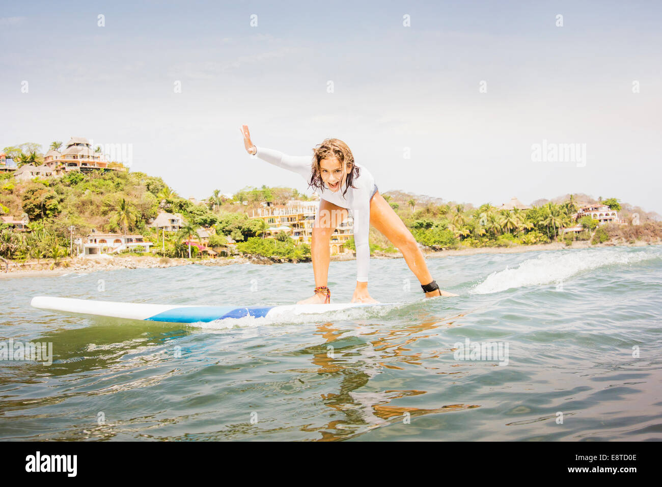 Mixed race girl surfing in waves Stock Photo