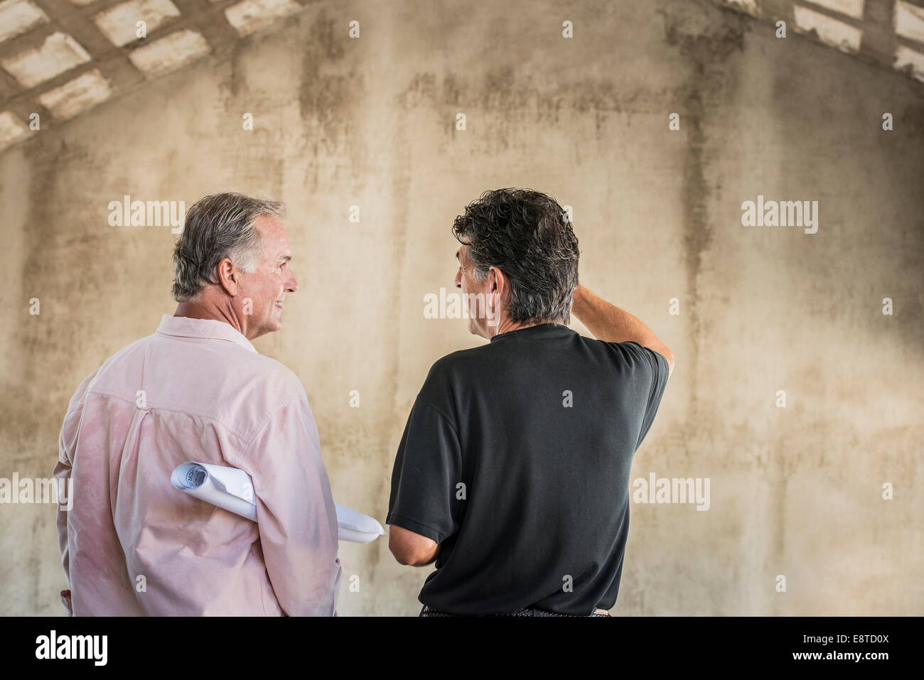 Caucasian architects talking near wall Stock Photo