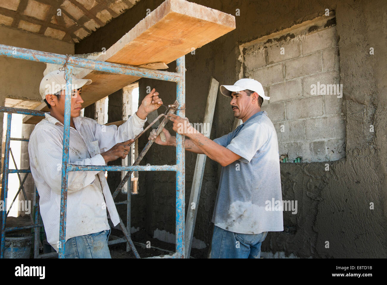 Hispanic construction workers with scaffolding at construction site Stock Photo
