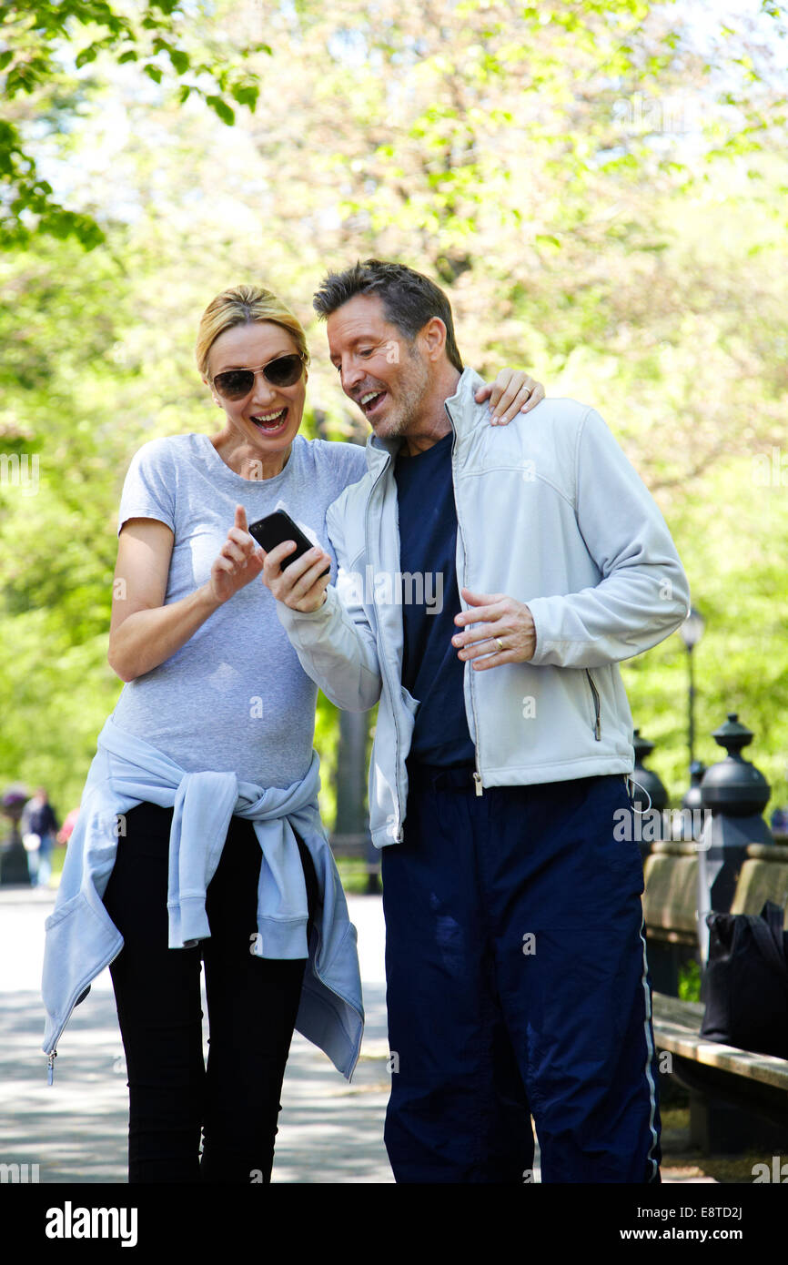 Caucasian couple using cell phone in park Stock Photo
