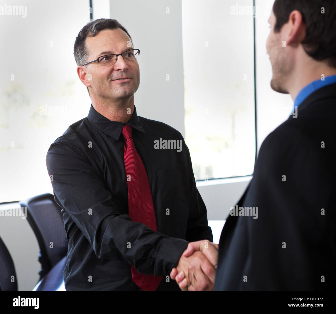 Businessmen shaking hands in office Stock Photo