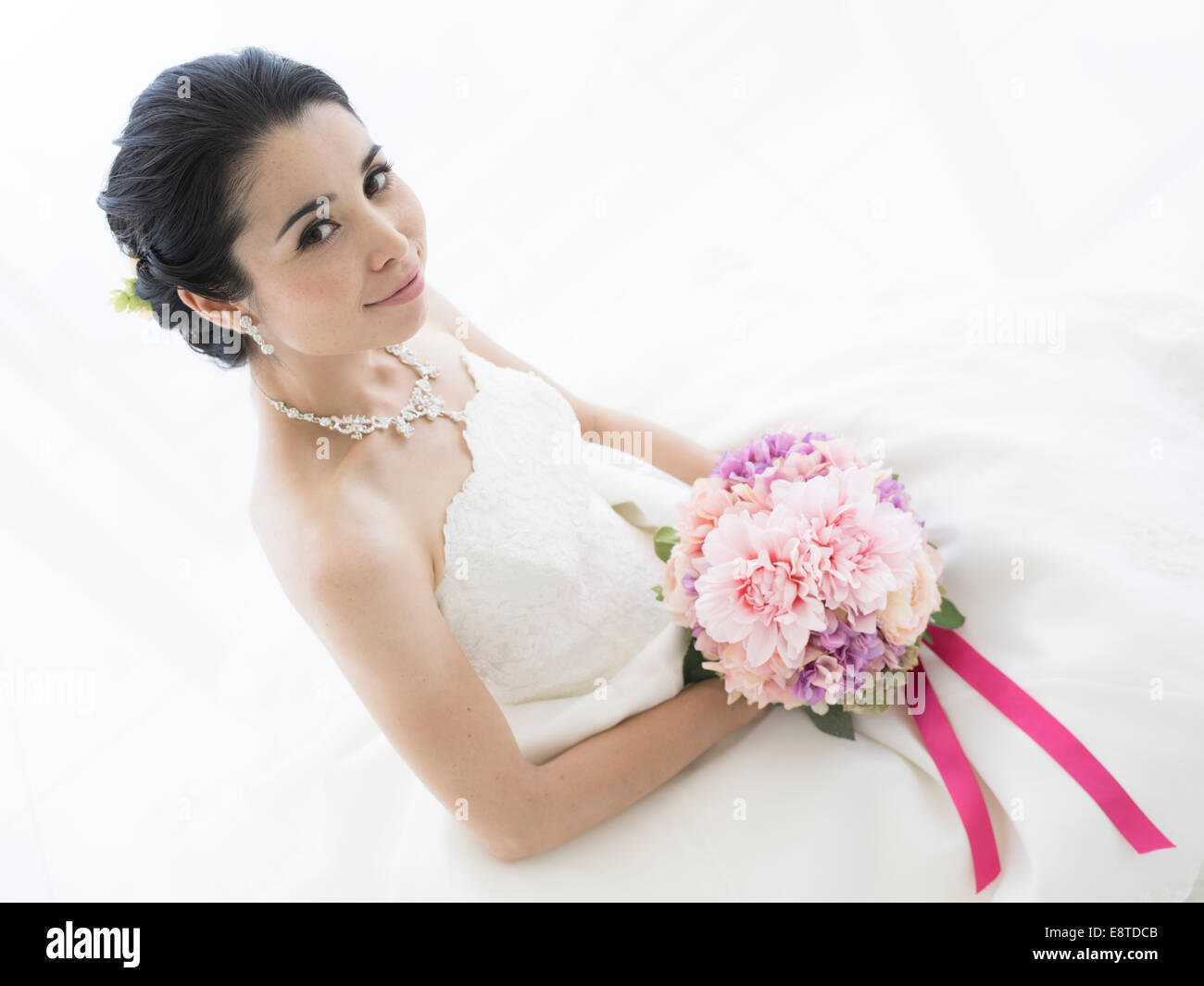 Mixed race, Asian / American bride in white wedding dress Stock Photo