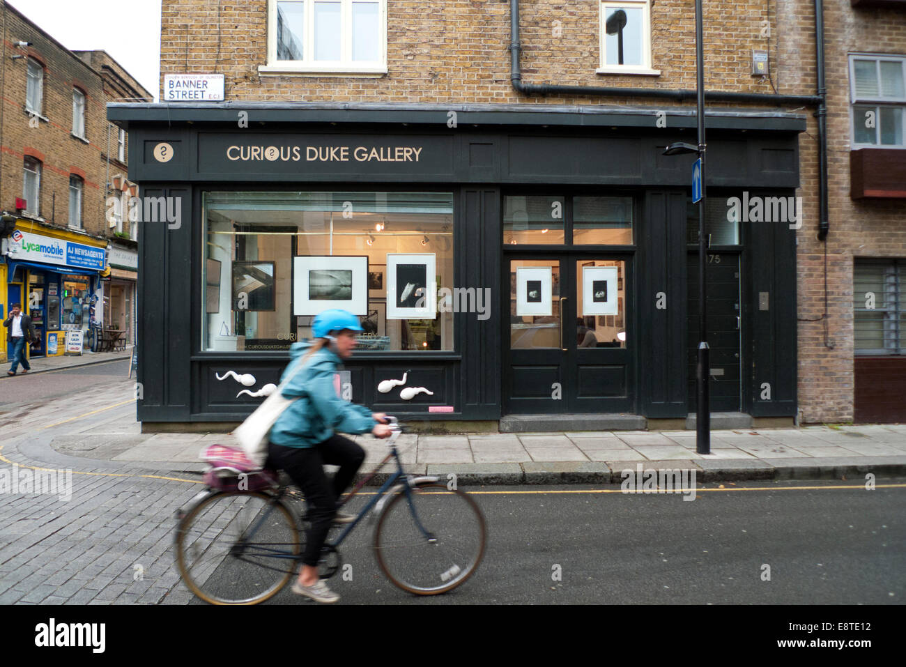 A cyclist passes the Curious Duke Gallery on the corner of Whitecross & Banner Street on a dry morning near the Barbican in the City of London. UK   KATHY DEWITT Stock Photo