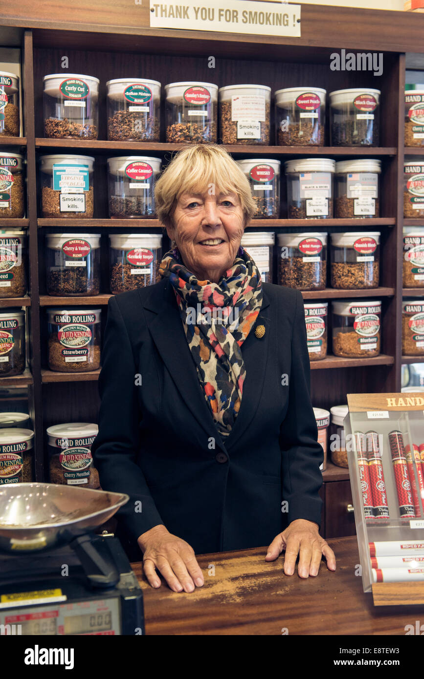 a female tobacconist lady sells, tobacco, cigarettes, loose tobacco, cigars etc from her specialist shop in brighton Stock Photo