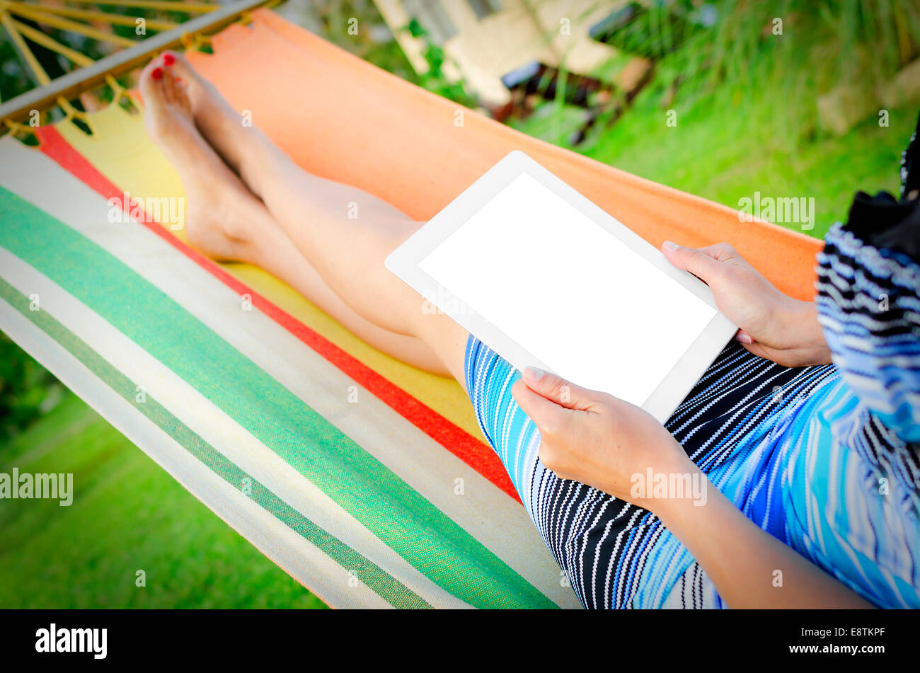 Woman Relaxing In Hammock With Tablet PC Stock Photo