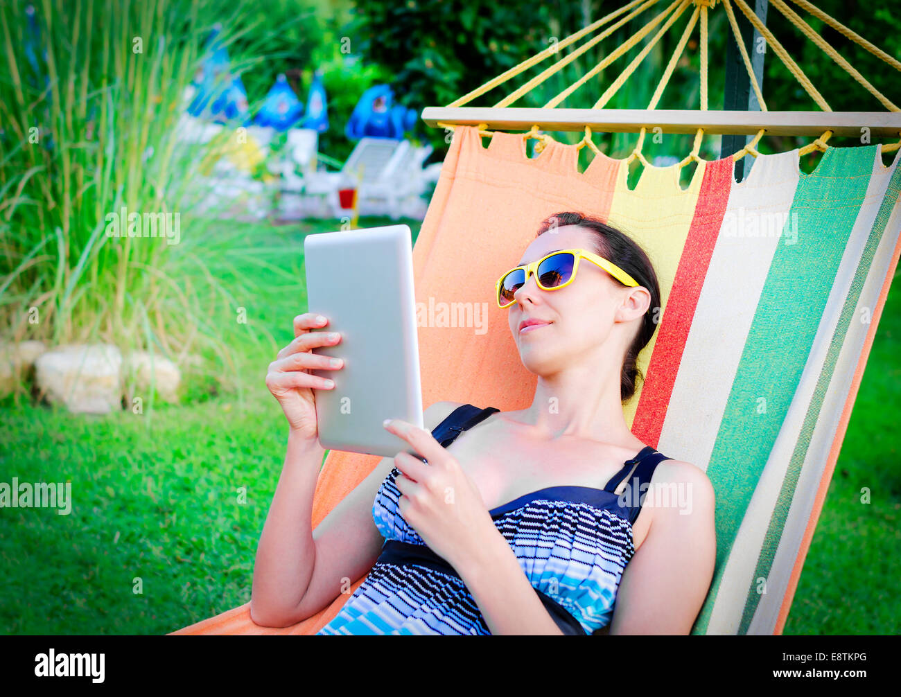 Woman Relaxing In Hammock With Tablet PC Stock Photo
