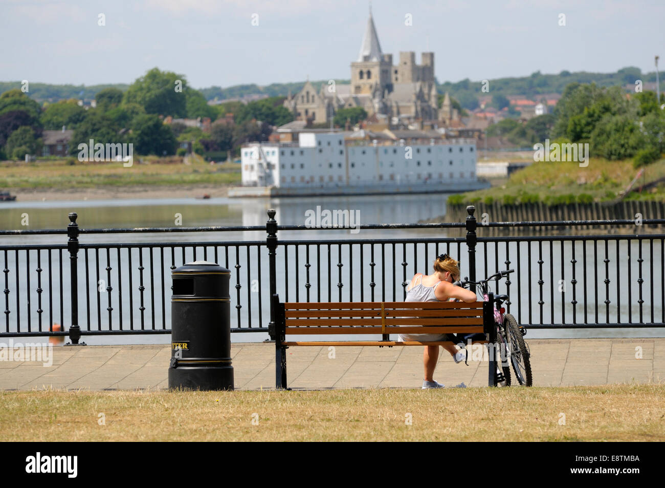 Chatham, Kent, England, UK. Rochester Cathedral seen from Chatham - woman on a bench and her bike Stock Photo