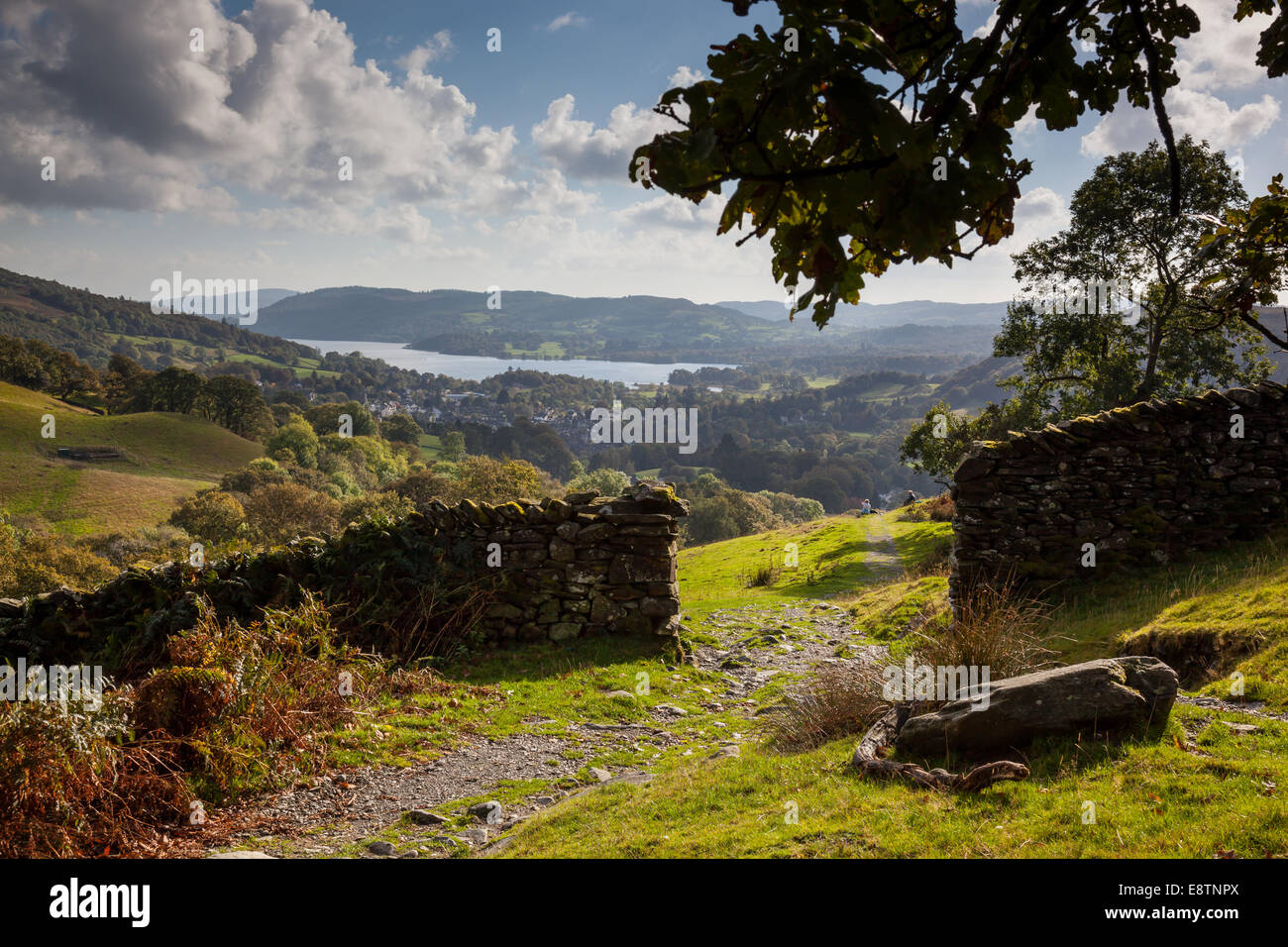 Walkers sitting beside path near a stone wall towards Lower Sweden Coppice, overlooking Ambleside, Lake District, Cumbria Stock Photo