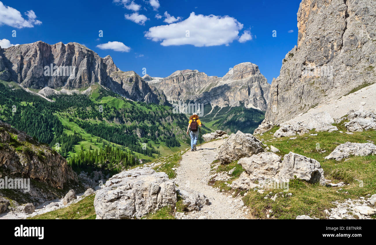 woman on footpath  in Sella mountain, on background Colfosco and Badia Valley, south Tyrol, Italy Stock Photo