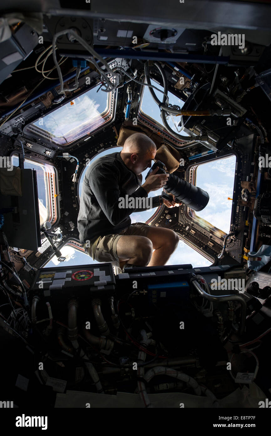 Inside the Cupola, NASA astronaut Chris Cassidy, an Expedition 36 flight engineer, uses a 400mm lens on a digital still camera to photograph a target of opportunity on Earth some 250 miles below him and the International Space Station. Cassidy has been ab Stock Photo