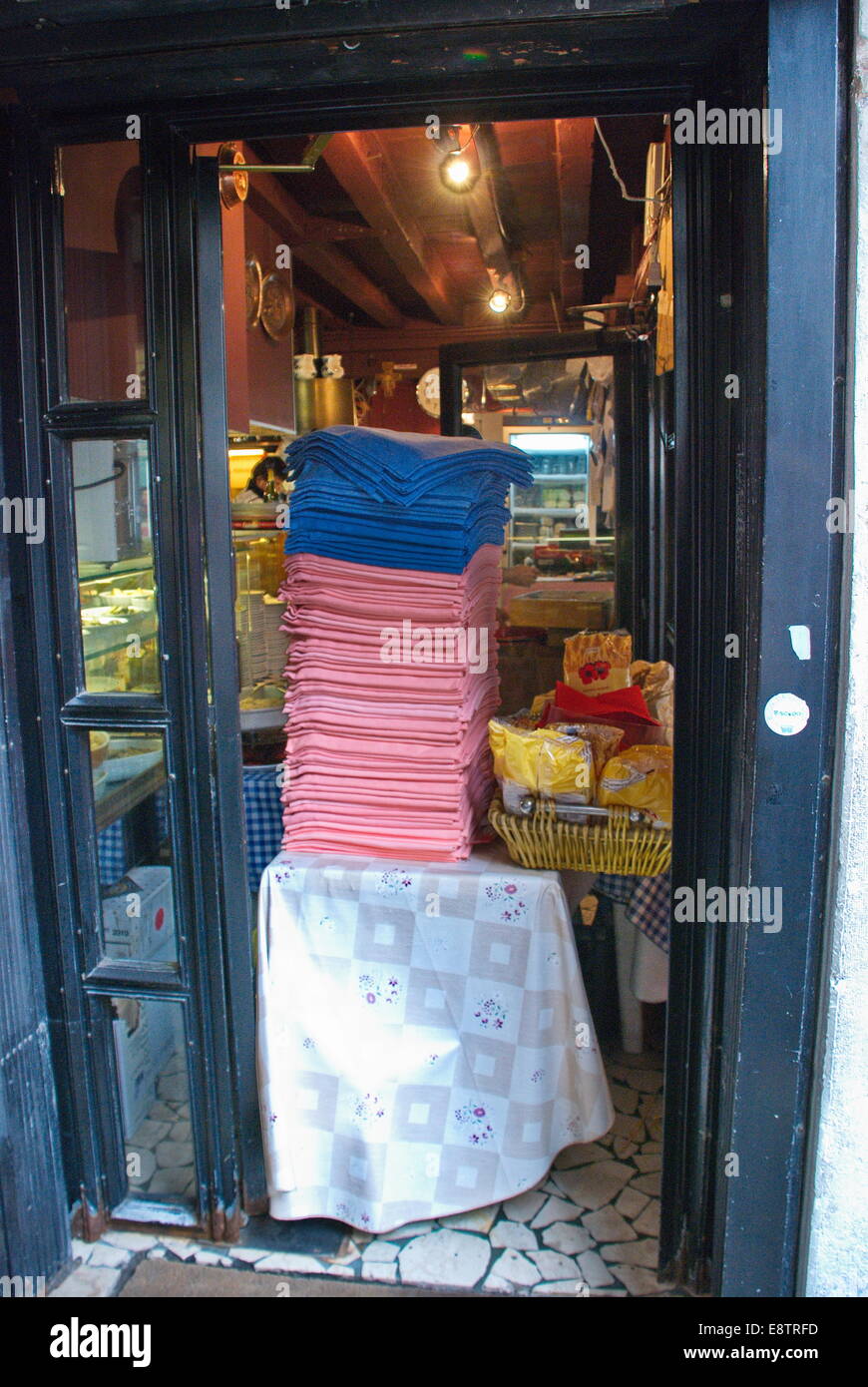 Colorful stack on linens in doorway of store in Venice, Italy. Stock Photo
