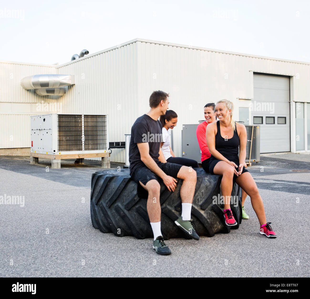 Fit Friends Conversing While Relaxing On Tire Stock Photo