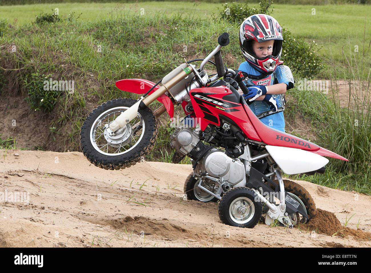 Young boy standing behind his dirt bike. It is stuck in the sand Stock