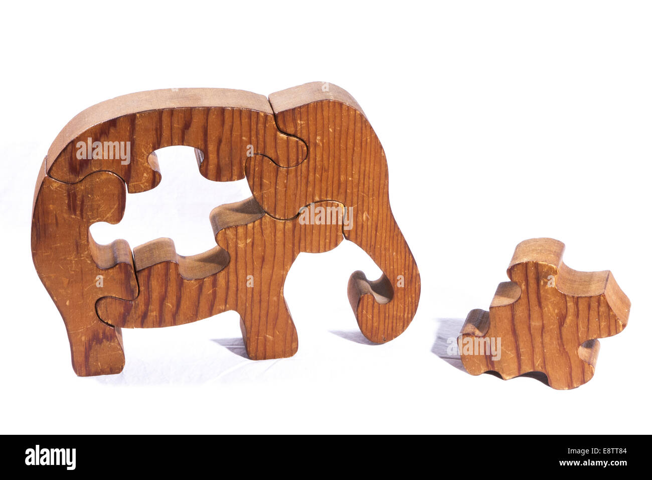Wooden Elephant puzzle with a piece laying on the table. Stock Photo