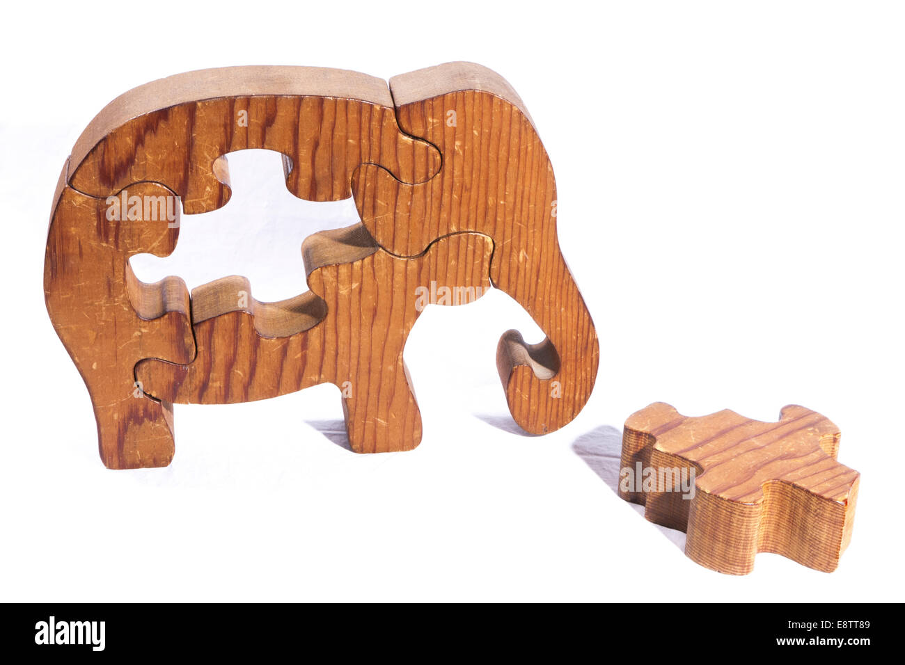 Wooden Elephant puzzle with a piece laying on the table. Stock Photo