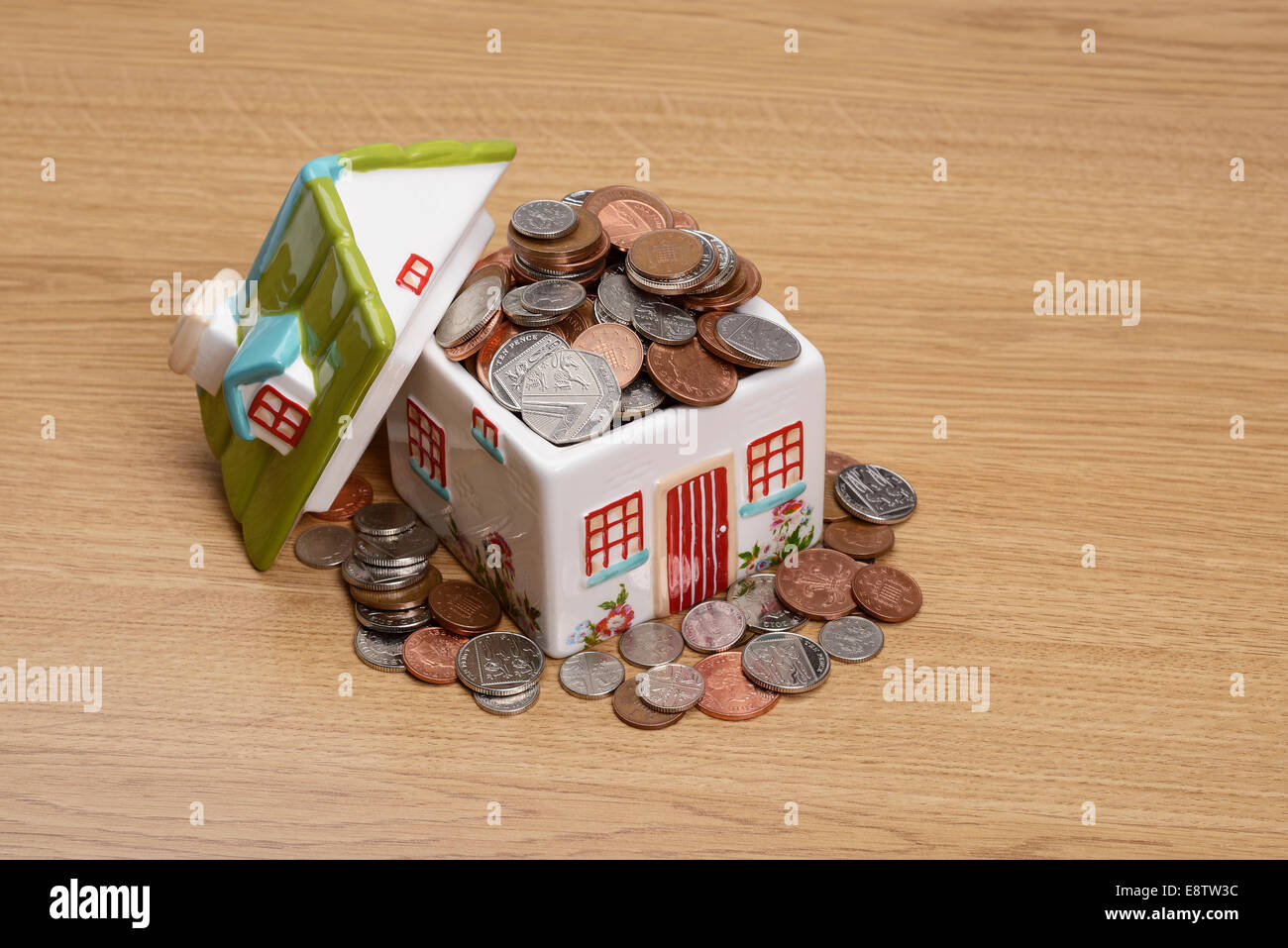 Ceramic house model filled with cash Stock Photo