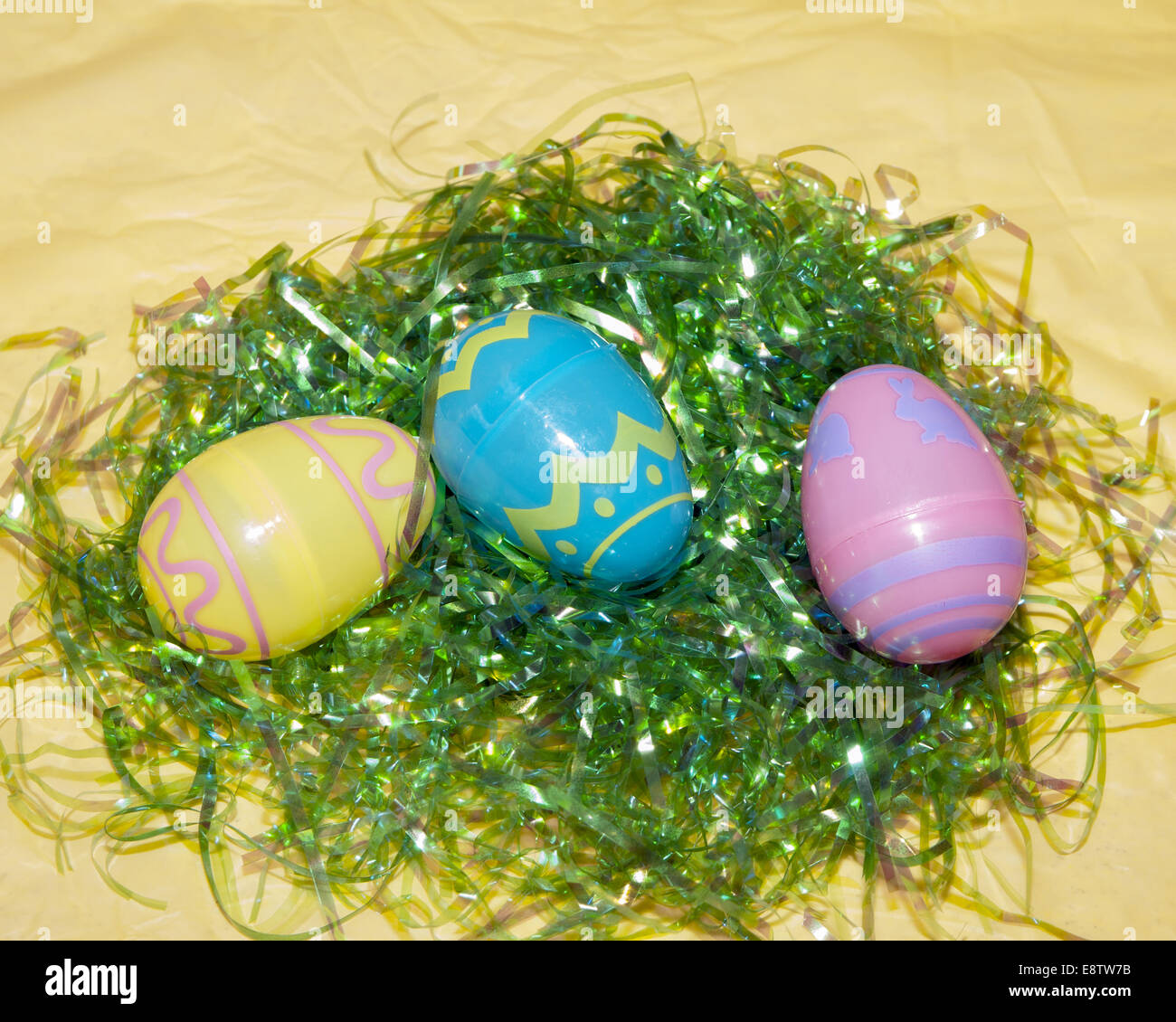 3 plastic easter eggs on green easter grass on a yellow table cloth Stock Photo