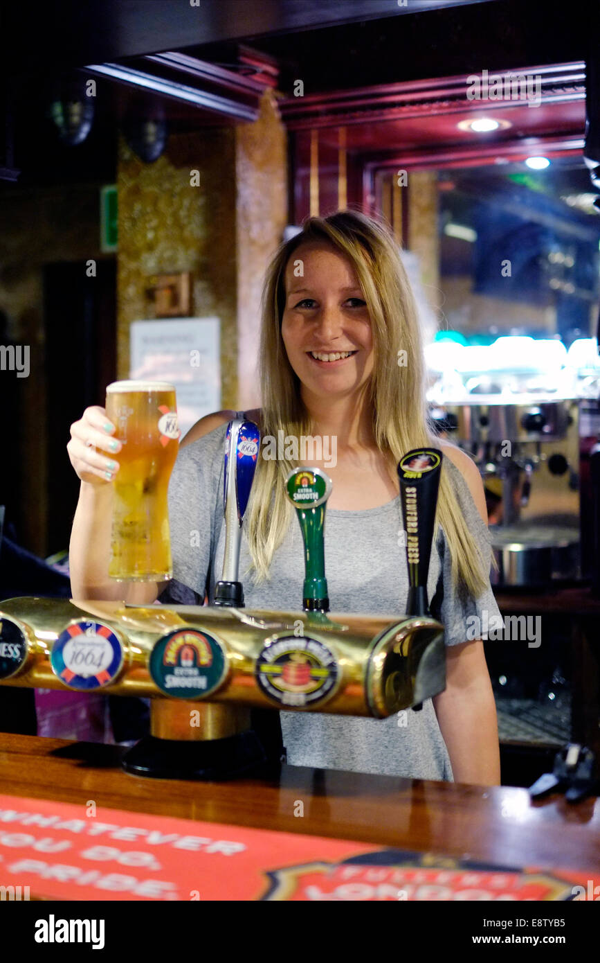 smiling young barmaid seving a pint of lager at a traditional british pub the eldon arms southsea england uk Stock Photo