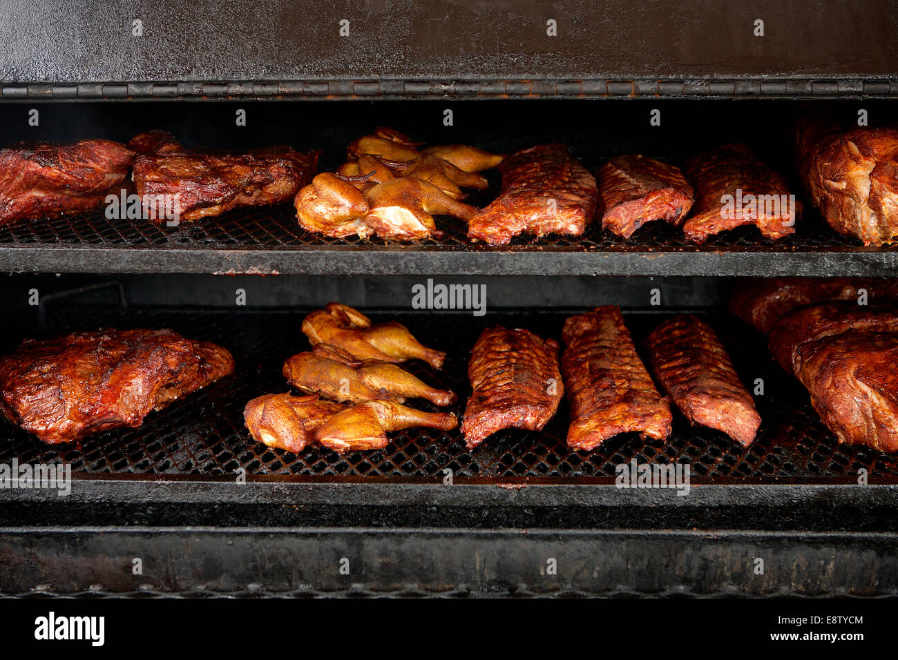 Chicken, Beef Brisket, and Pork Ribs in the smoker. Stock Photo