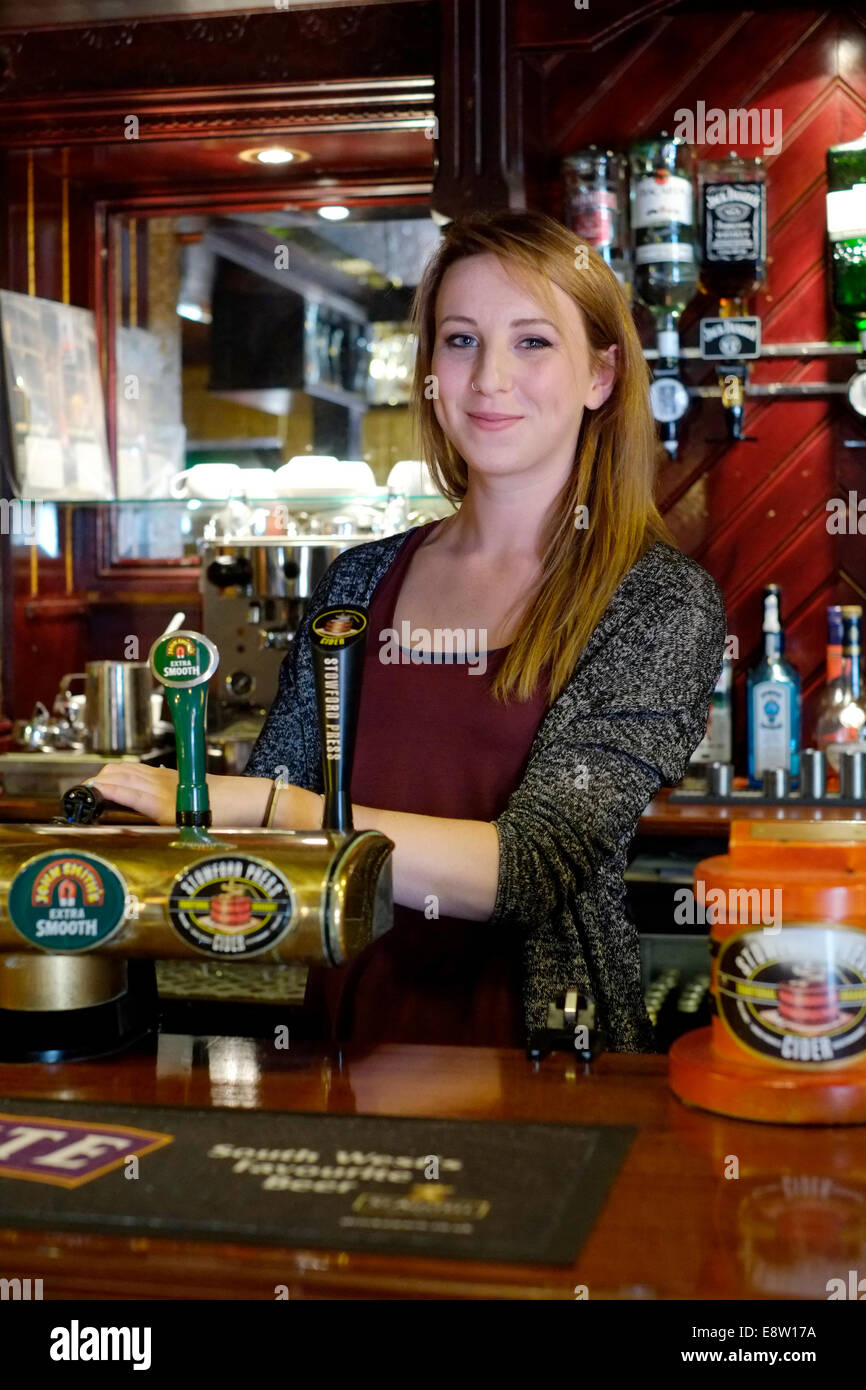 smiling barmaid pouring a pint of beer in a traditional british pub the
