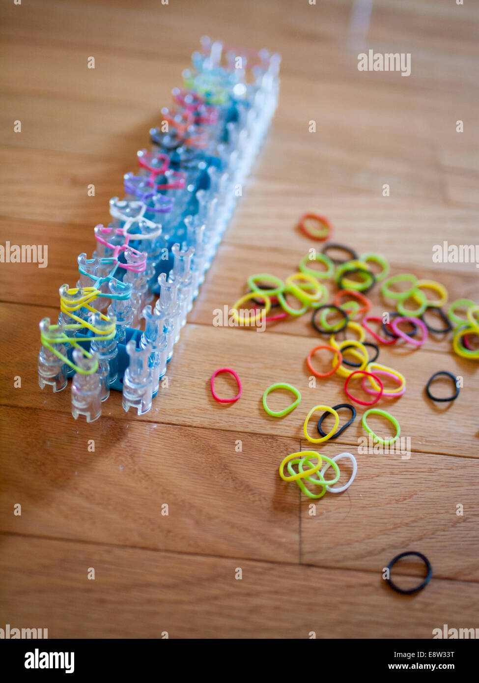 A Rainbow Loom and colourful rubber bands.  Rainbow loom is a plastic loom used to weave rubber bands into bracelets and charms. Stock Photo