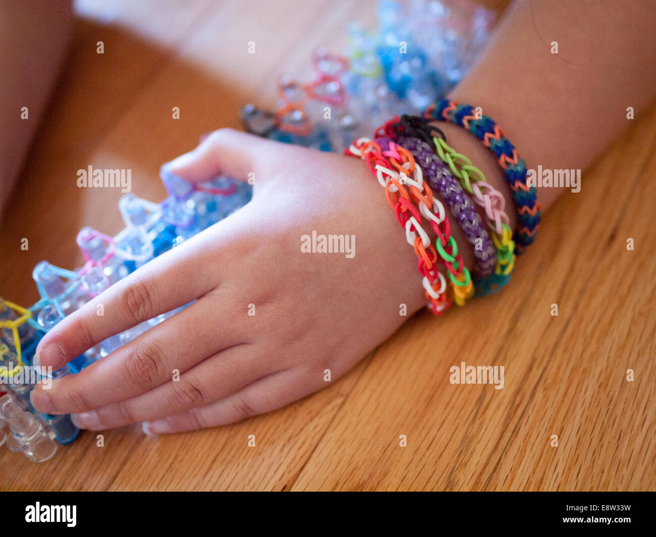 A little girl shows her Rainbow Loom bracelets. Rainbow Loom is a toy loom used to weave rubber bands into bracelets and charms. Stock Photo