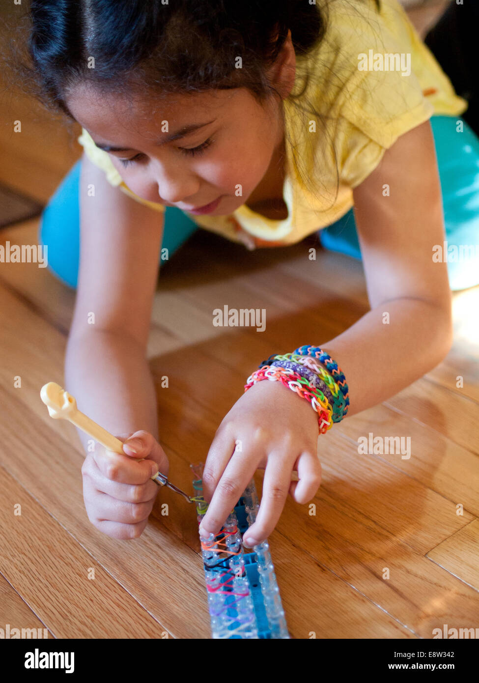 A cute little girl weaves a bracelet using a Rainbow Loom, a popular toy  used to weave rubber bands into bracelets and charms Stock Photo - Alamy