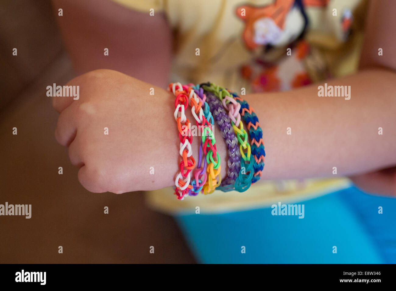 A little girl shows her Rainbow Loom bracelets. Rainbow Loom is a toy loom used to weave rubber bands into bracelets and charms. Stock Photo