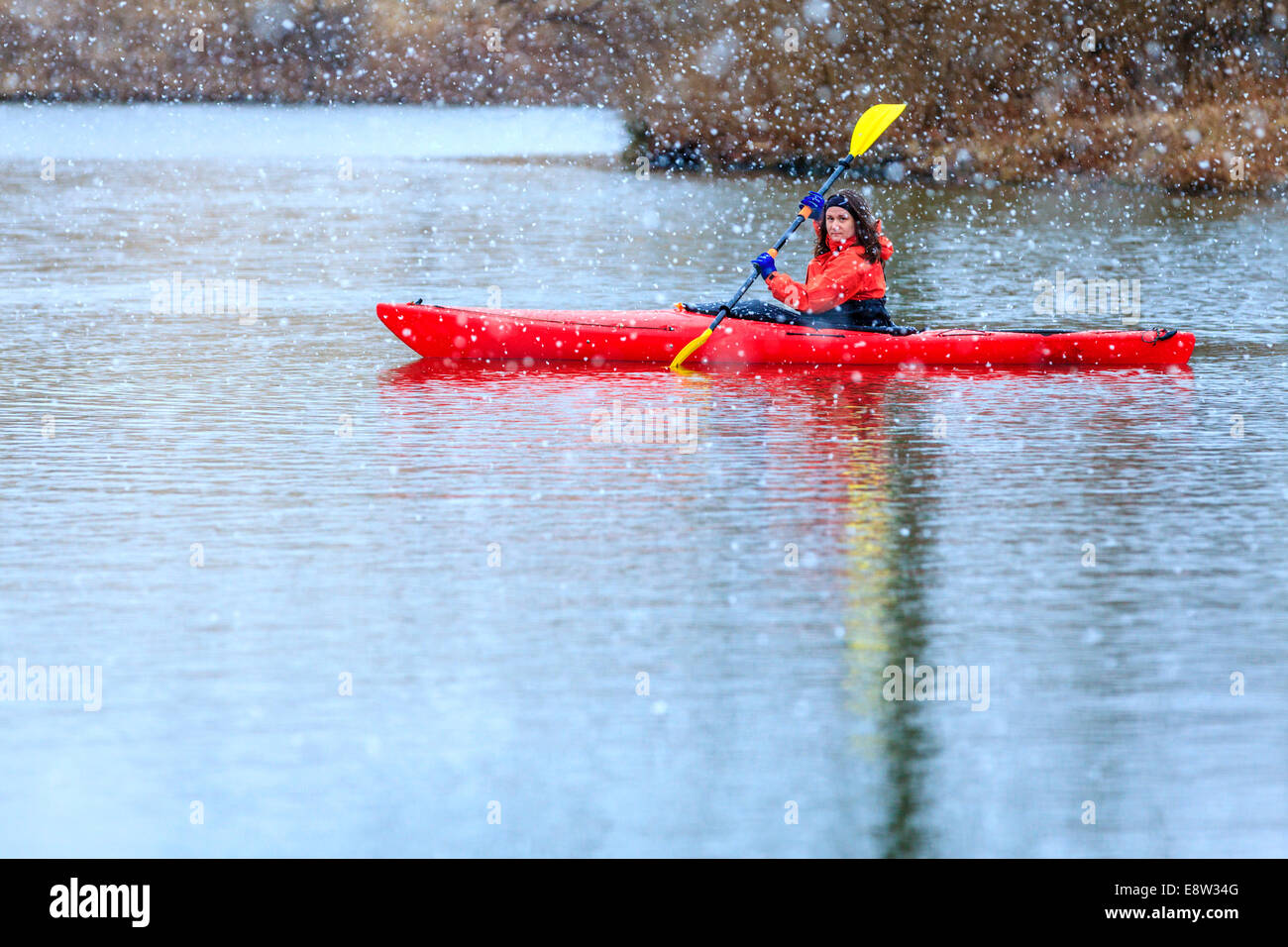 Woman is kayaking on a lake under heavy snow Stock Photo